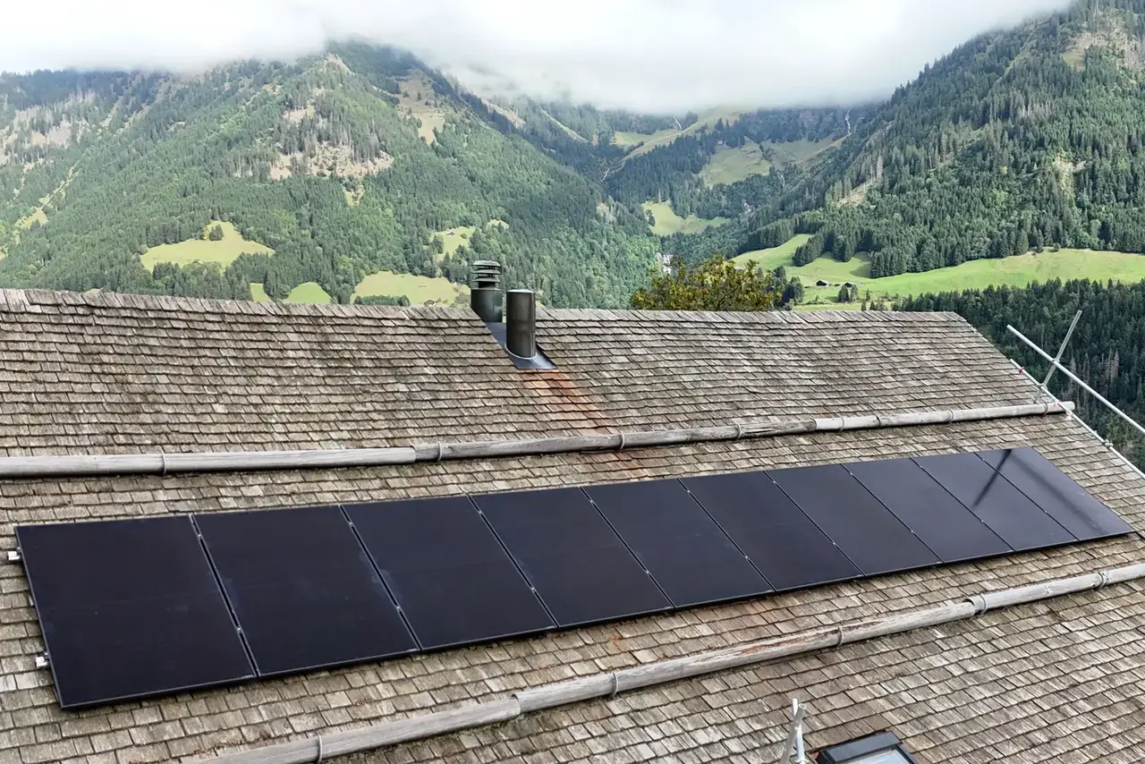 Panneaux photovoltaïques posés par Abelarti sur un toit en tavillons à Champéry, vallée en arrière-plan